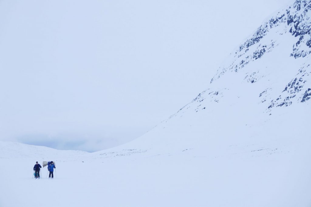 Två människor skidar bredvid ett stort fjäll