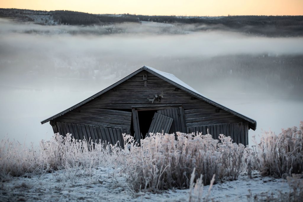 En fallfärdig lada i morgonljus med frost