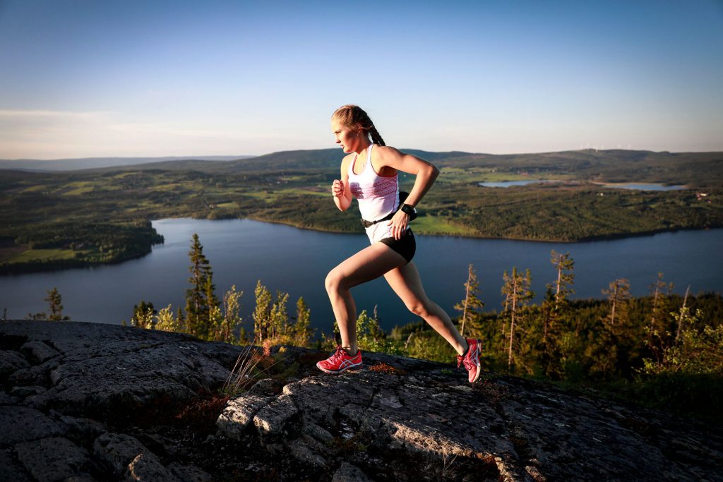 En flicka som löptränar och springer på ett berg