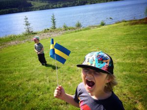 Två barn som viftar med svenska flaggan under nationaldagen